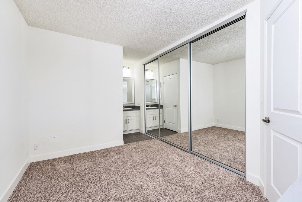 an empty bedroom with mirrored closet doors and carpeting