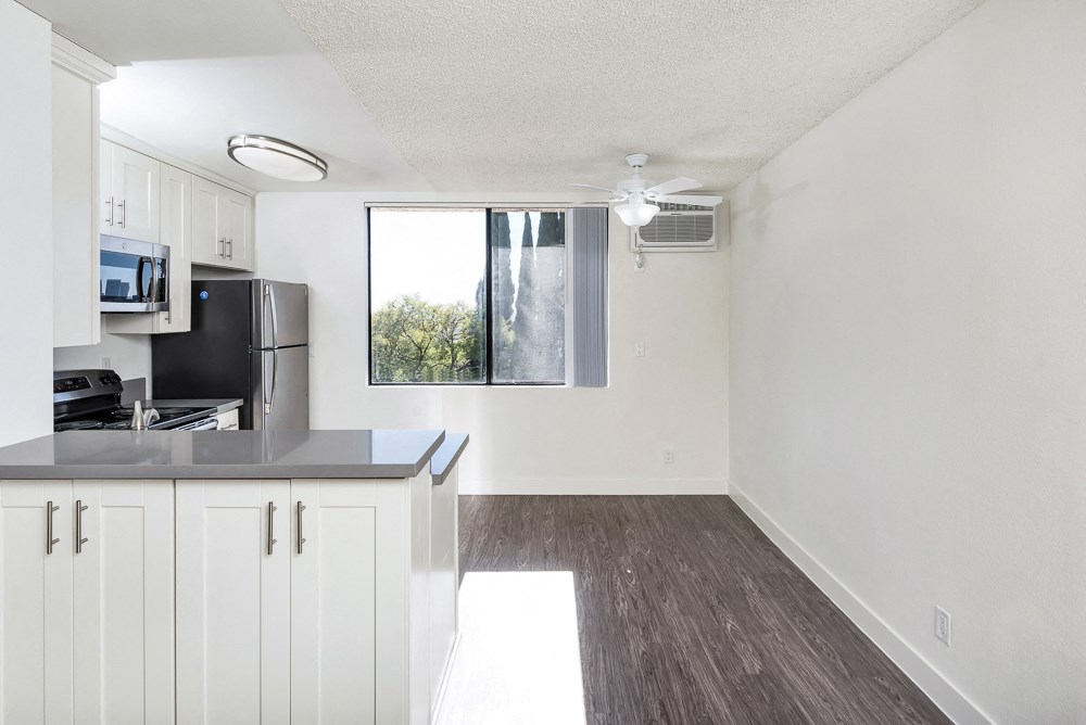 an empty kitchen with white cabinets and a window