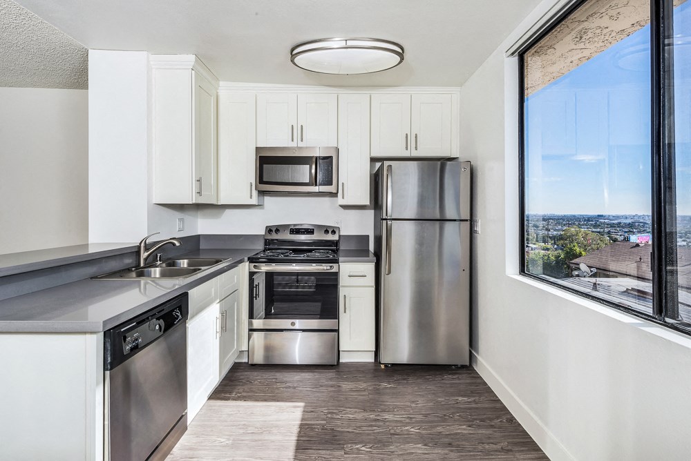 an empty kitchen with stainless steel appliances and a large window