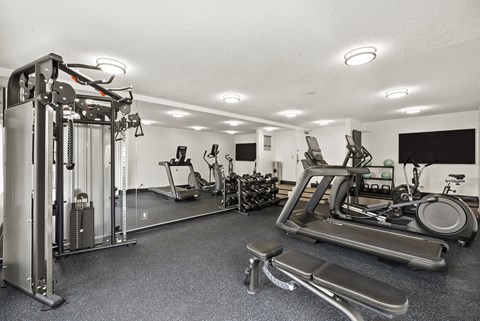 A black and white photo of a gym with a treadmill, weights, and other exercise equipment.