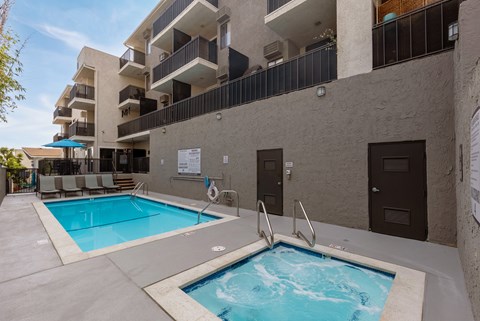 A small pool with a hot tub in front of a building.