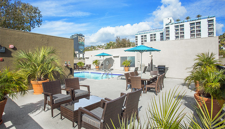 a swimming pool with chairs and umbrellas on a patio