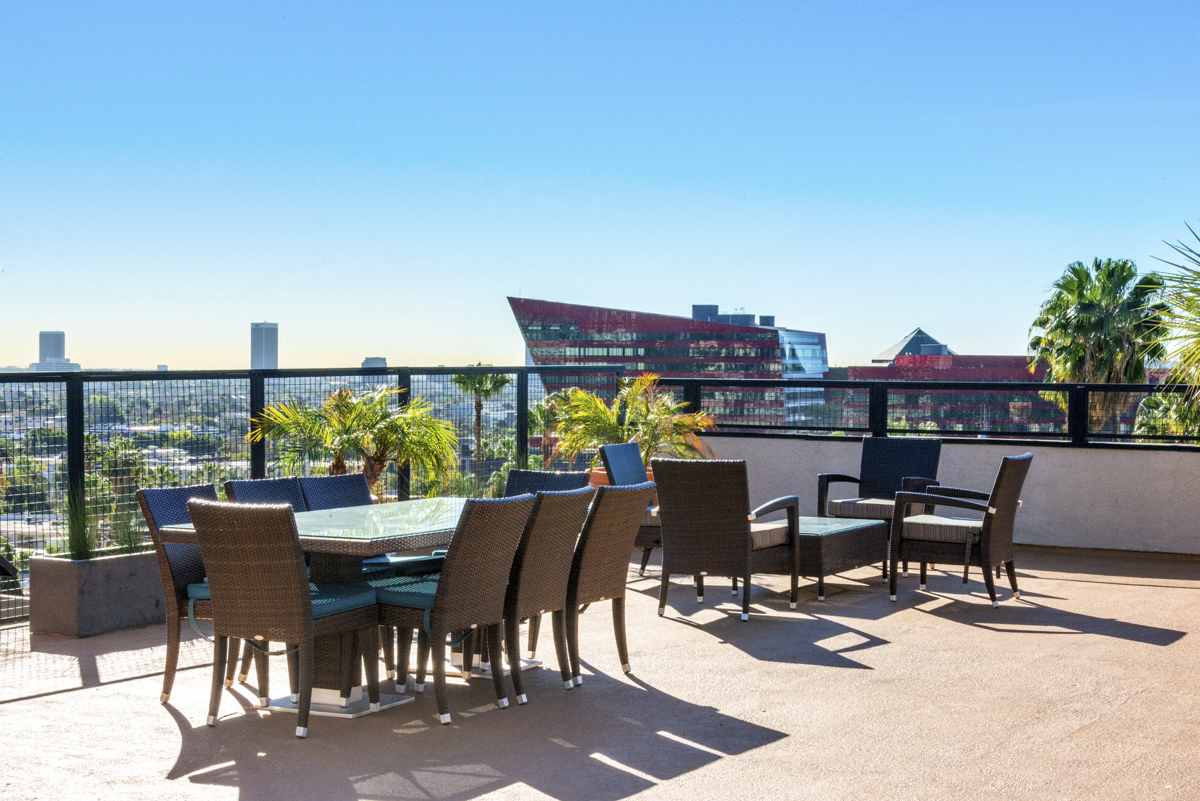 a large table and chairs on a balcony with a view of the city