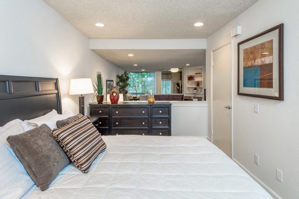 a bedroom with a bed and a dresser and a bathroom