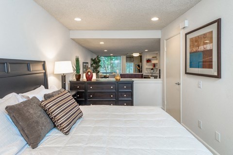 a bedroom with a bed and a dresser and a bathroom