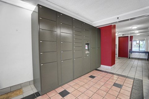 A row of grey lockers in a room with a red door.