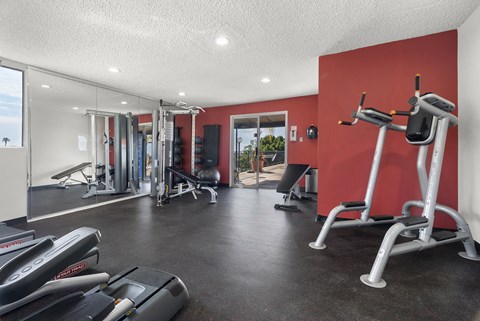 A gym with a red wall and various exercise equipment.
