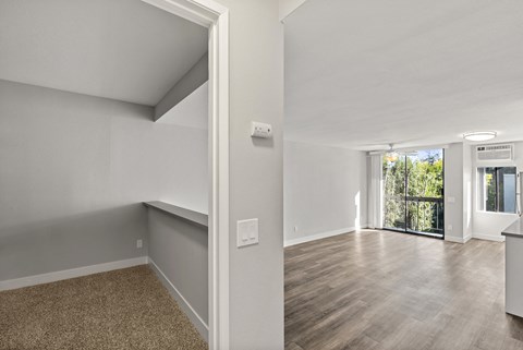 A room with a carpeted floor and a wooden floor leading to a balcony.