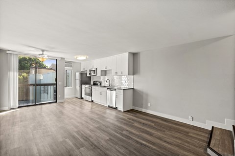 A kitchen with white cabinets and a wooden floor.