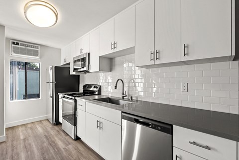 A modern kitchen with white cabinets and stainless steel appliances.