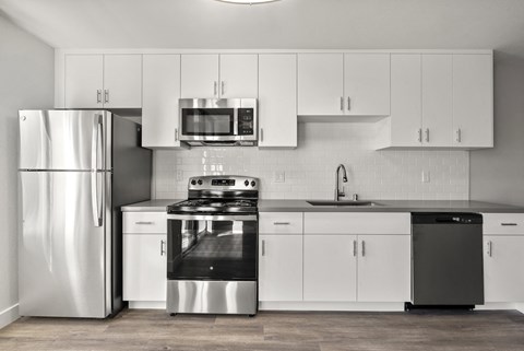 A modern kitchen with white cabinets and stainless steel appliances.