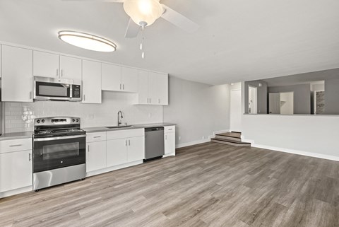 A spacious kitchen with white cabinets and a wood floor.