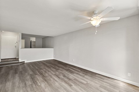 A room with a ceiling fan and light fixture, and a wooden floor.