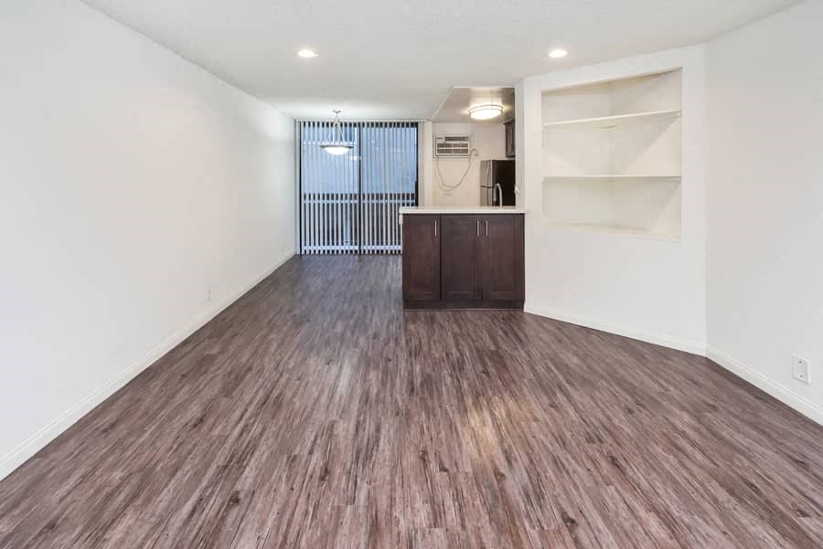 an empty living room with wood flooring and white walls
