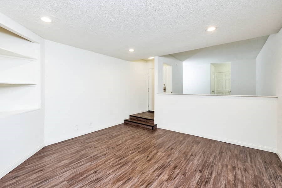an empty living room with white walls and wood flooring