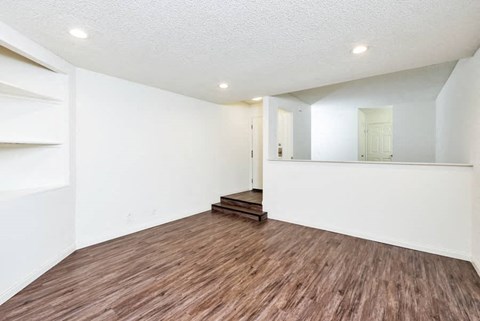an empty living room with white walls and wood flooring