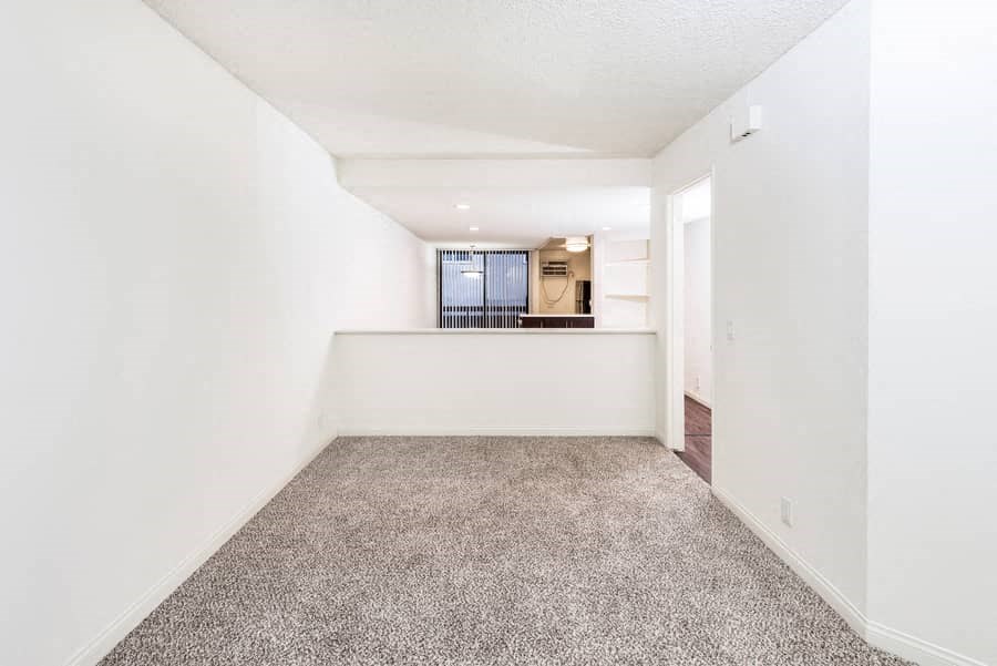 an empty living room with white walls and carpet