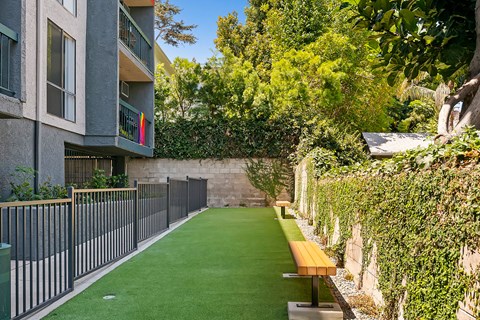a green lawn in front of an apartment building with a fence