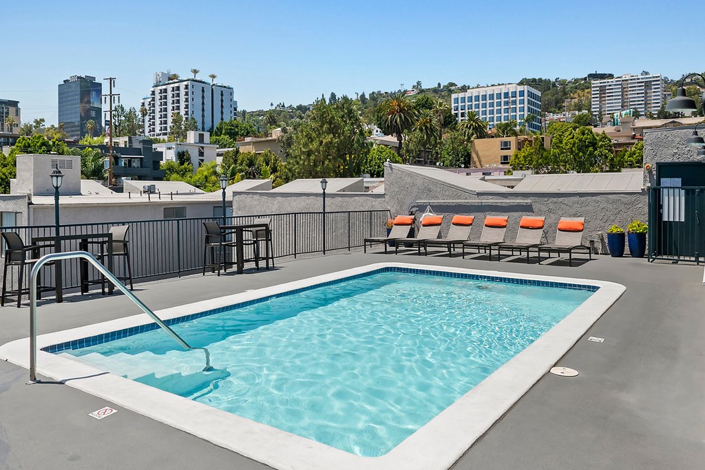 a pool on the roof of a building with a city in the background