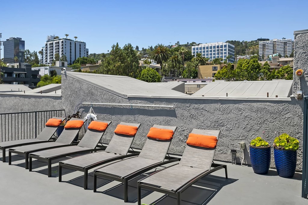 a row of lounge chairs on a rooftop overlooking the city