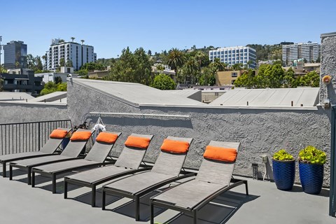 a row of lounge chairs on a rooftop overlooking the city