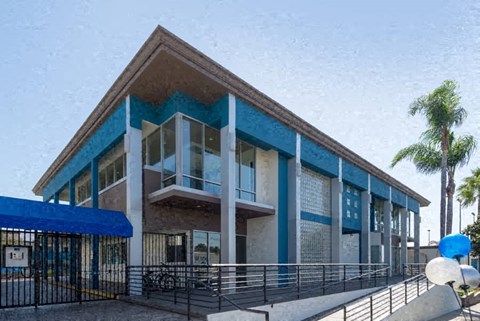 the front of a building with a fence and palm trees