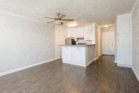 an empty living room and kitchen with a ceiling fan