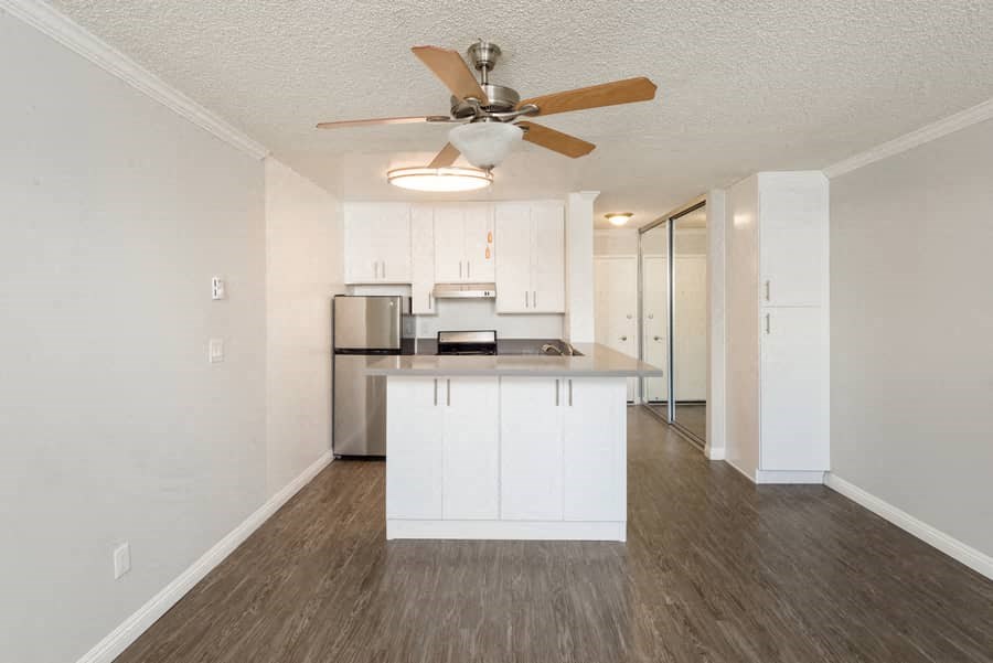 a white kitchen with a ceiling fan and a counter top