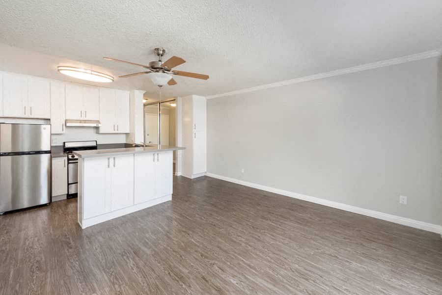 an empty living room and kitchen with a ceiling fan