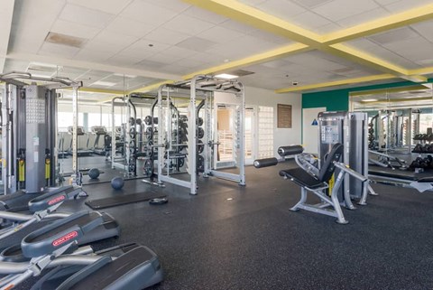 a gym with cardio equipment and weights on the floor