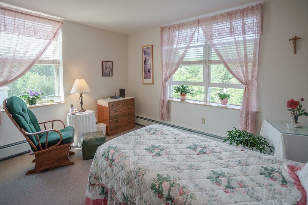 a bedroom with a bed and a chair and a window