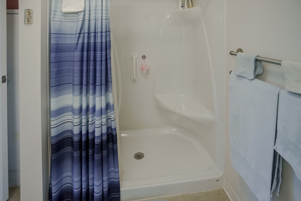 a bathroom with a shower and a blue shower curtain