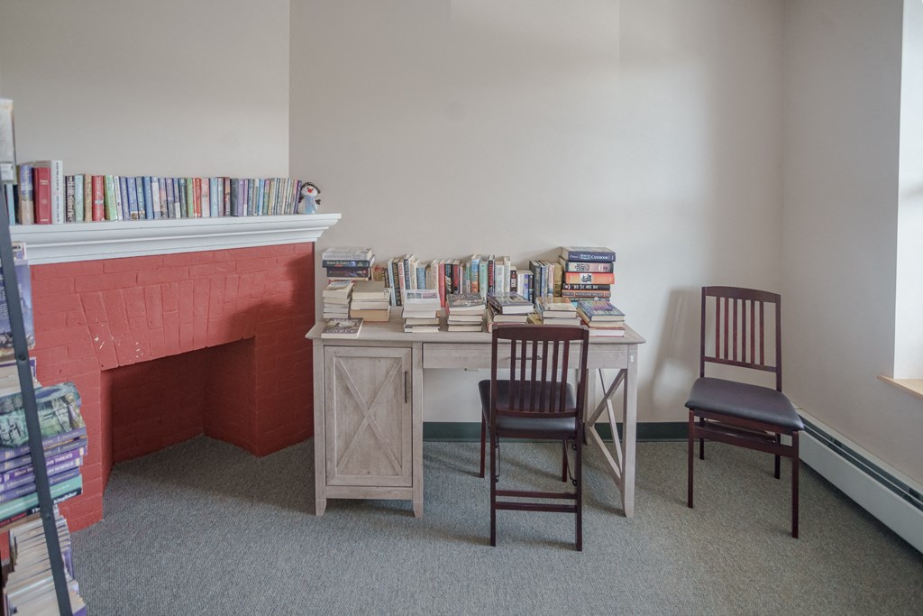 a room with a desk with two chairs and a bookshelf filled with books