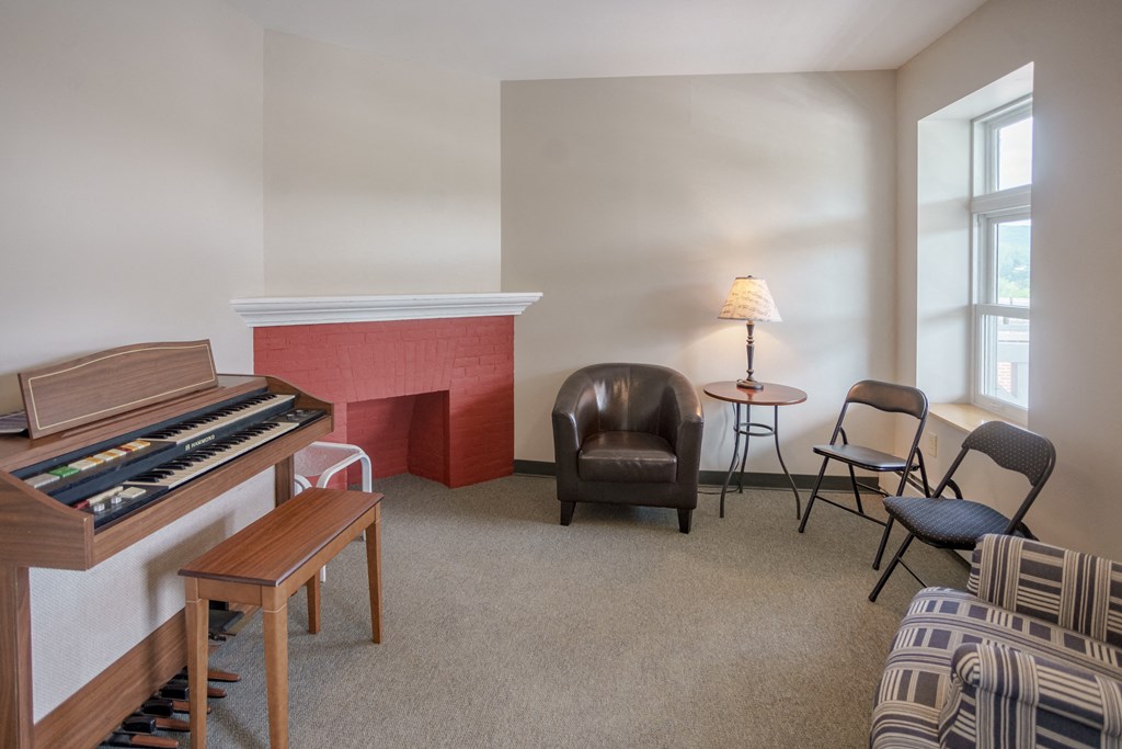 a living room with a piano and chairs and a table