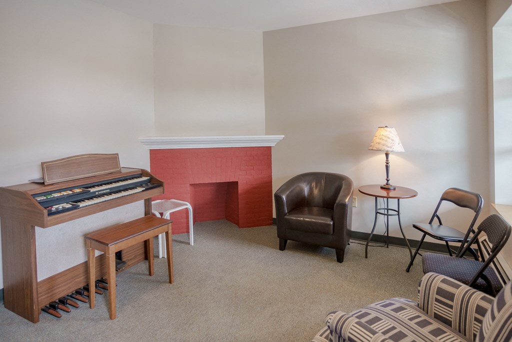 a living room with a piano and a table with chairs
