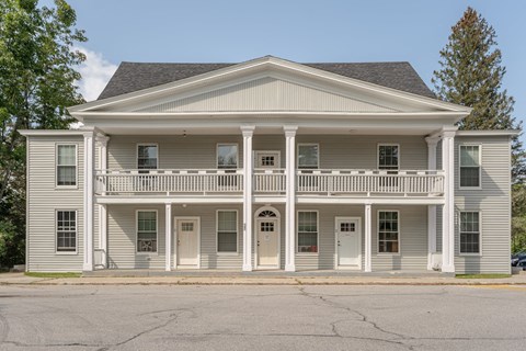the front of a white house with a balcony