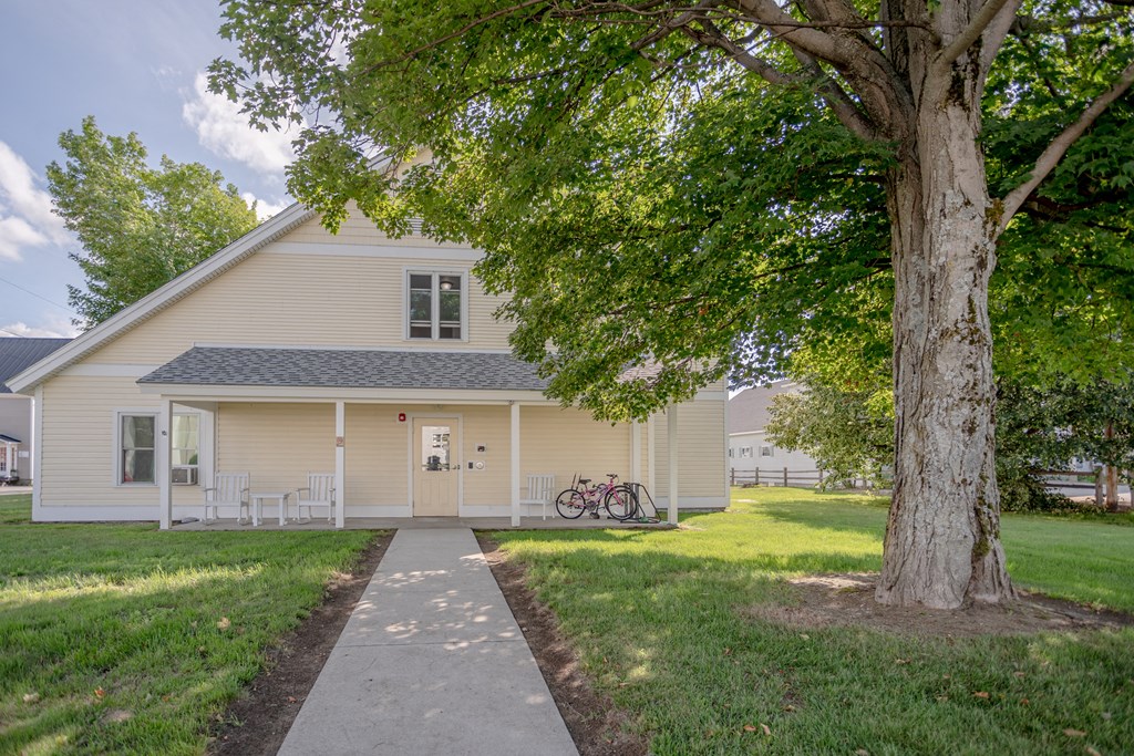 a white house with a tree and a sidewalk in front of it