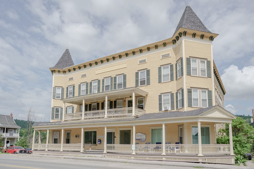 a large yellow building with a cone shaped roof on a street