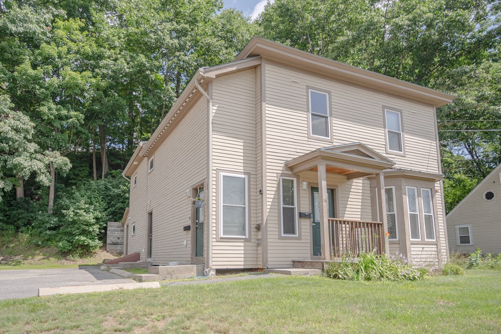 the front of a yellow house with trees in the background