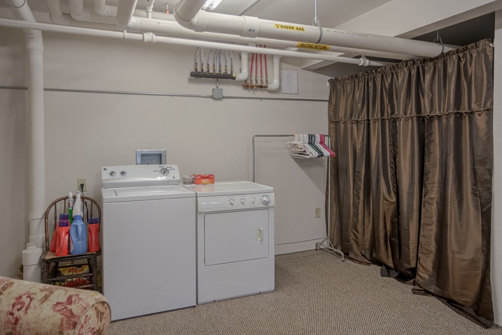 a laundry room with a washer and dryer in it and a brown curtain