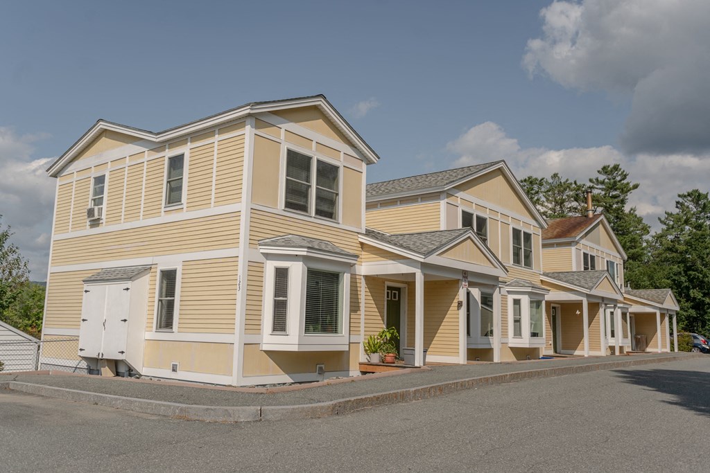 a row of yellow houses with a street in front of them