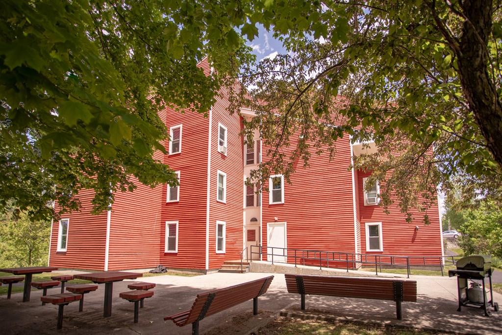a large red building with benches and trees in front of it