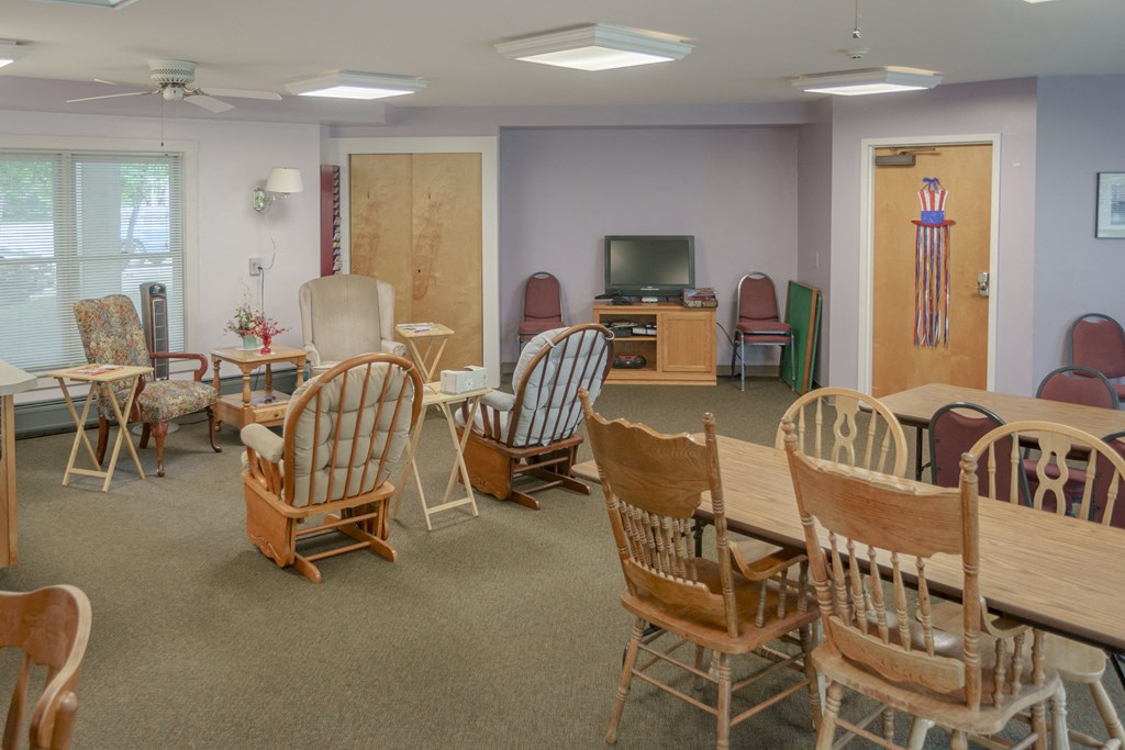 a multipurpose room with tables and chairs and a television