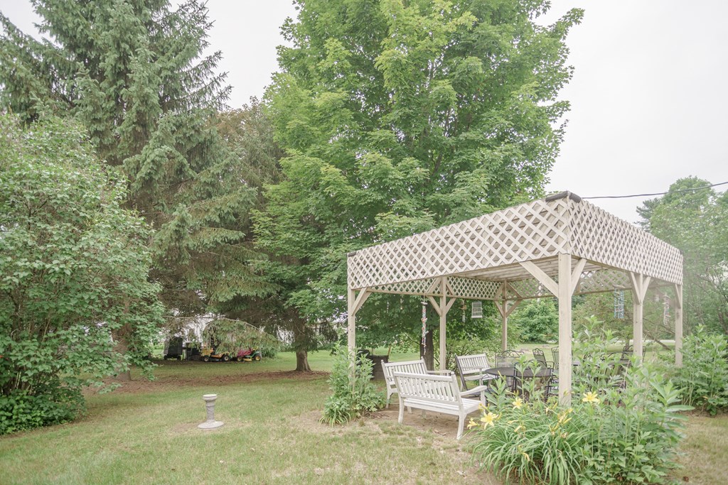 a pergola with a table and chairs in a garden