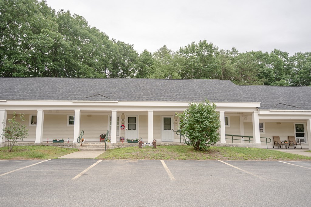 a large white building with a porch and a parking lot