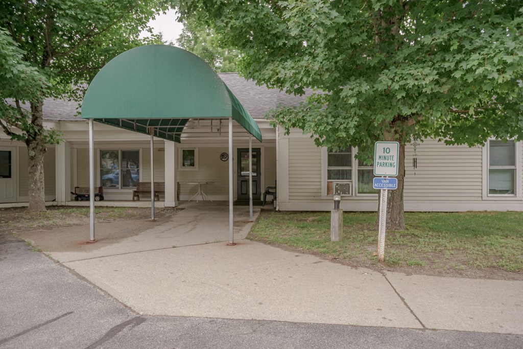 a house with a green awning and a sidewalk in front of it