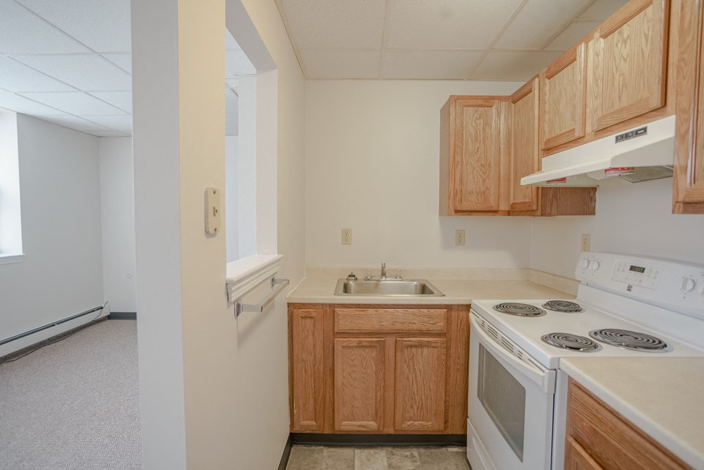 an empty kitchen with white appliances and wooden cabinets