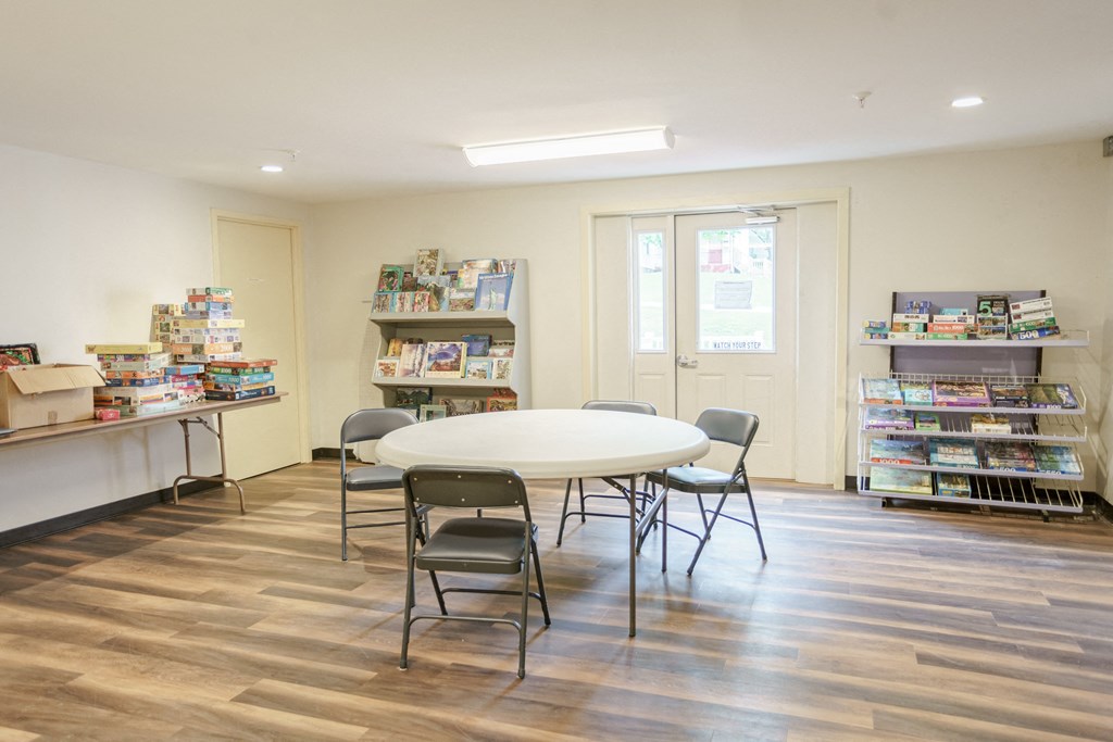a library with a white table and chairs and shelves of books