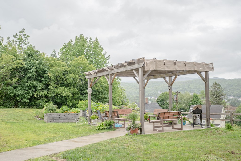 a pavilion in a park with benches and a grill