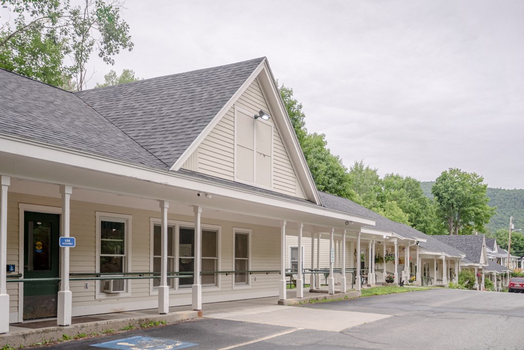 the front of a building with a porch and a parking lot